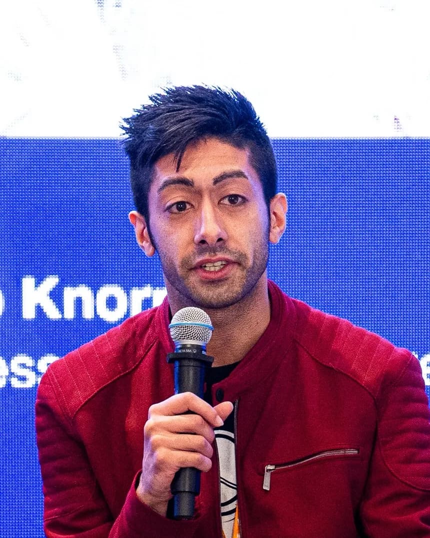 Naeem Shabir speaking into a microphone on a panel stage